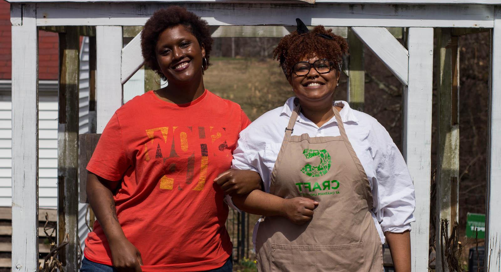 Photo fo two smiling women linking arms. One is wearing an apron with the CRAFT logo.